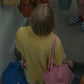 A woman wearing yellow pyjamas, wearing HÔTEL827 Sun Kissed pink canvas tote bag over shoulder