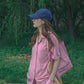 A woman wearing a pink casual wear set, wearing HÔTEL827 Sun Kissed pink canvas tote bag over shoulder with Hotel827 sun kissed blue baseball cap.