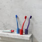 HAY Tann toothbrushes in assorted colours in tooshbrush holders on marble shelf. 