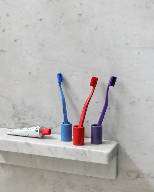 HAY Tann toothbrushes in assorted colours in tooshbrush holders on marble shelf. 