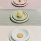 Stack of Hay barro plates with fruits on a pastel-colored surface