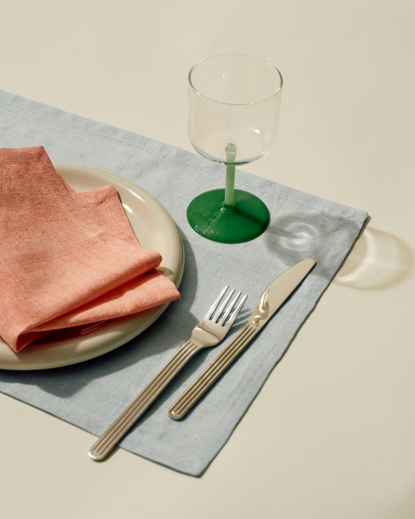 Table setting with the HAY Tint Wine Glasses, showcasing minimalist clear borosilicate glass bowls resting on delicate stems in jade light green and jade dark green.