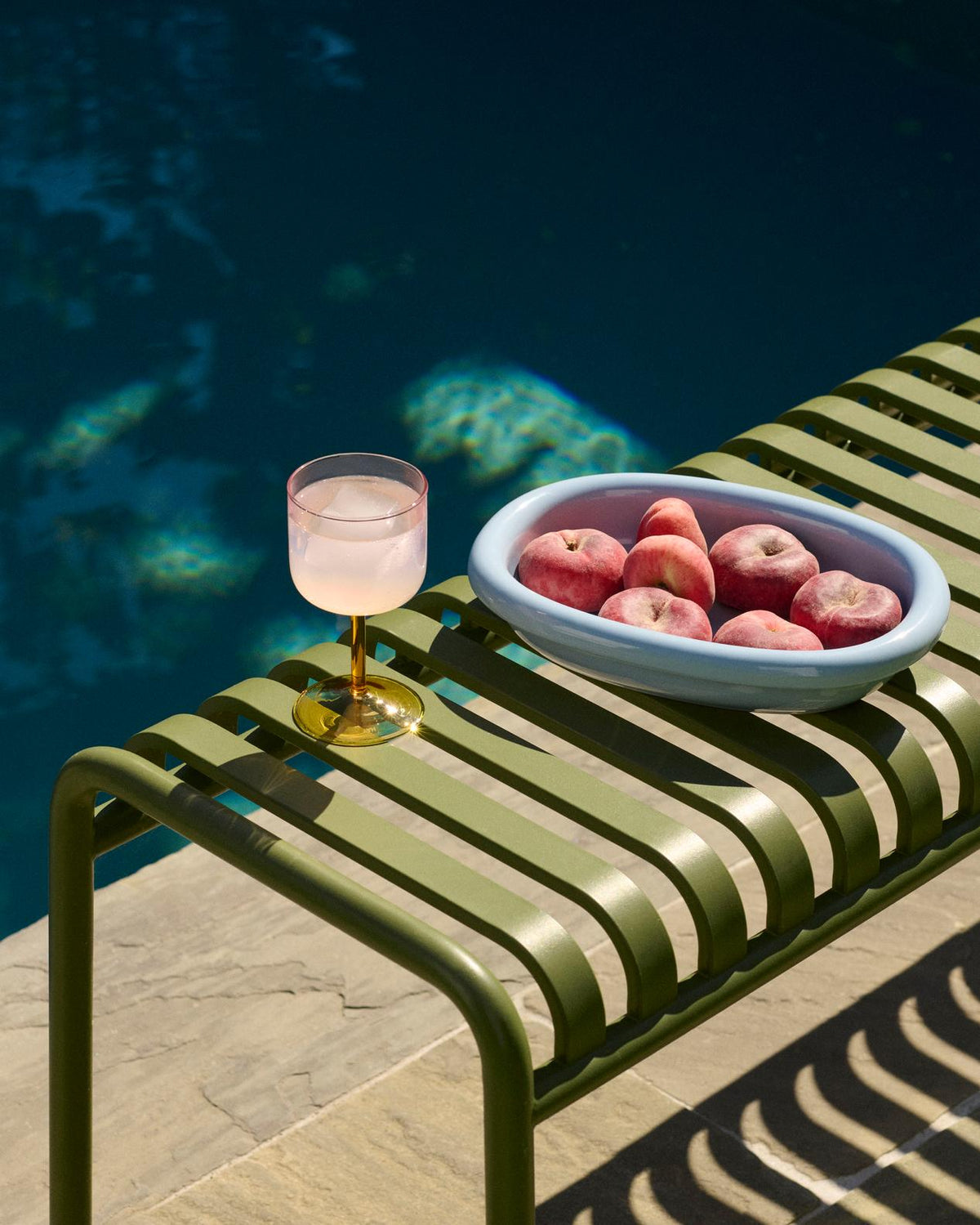 HAY Barro light blue terracotta oval dish with peaches on a outdoor chair near the pool.