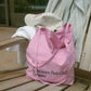 HÔTEL827 Sun Kissed Pink washed cotton shoulder bag with French typography, pairs with Apres baseball cap on outdoor chair. 