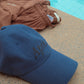 HÔTEL827 Sun Kissed blue baseball cap nearby a pool.
