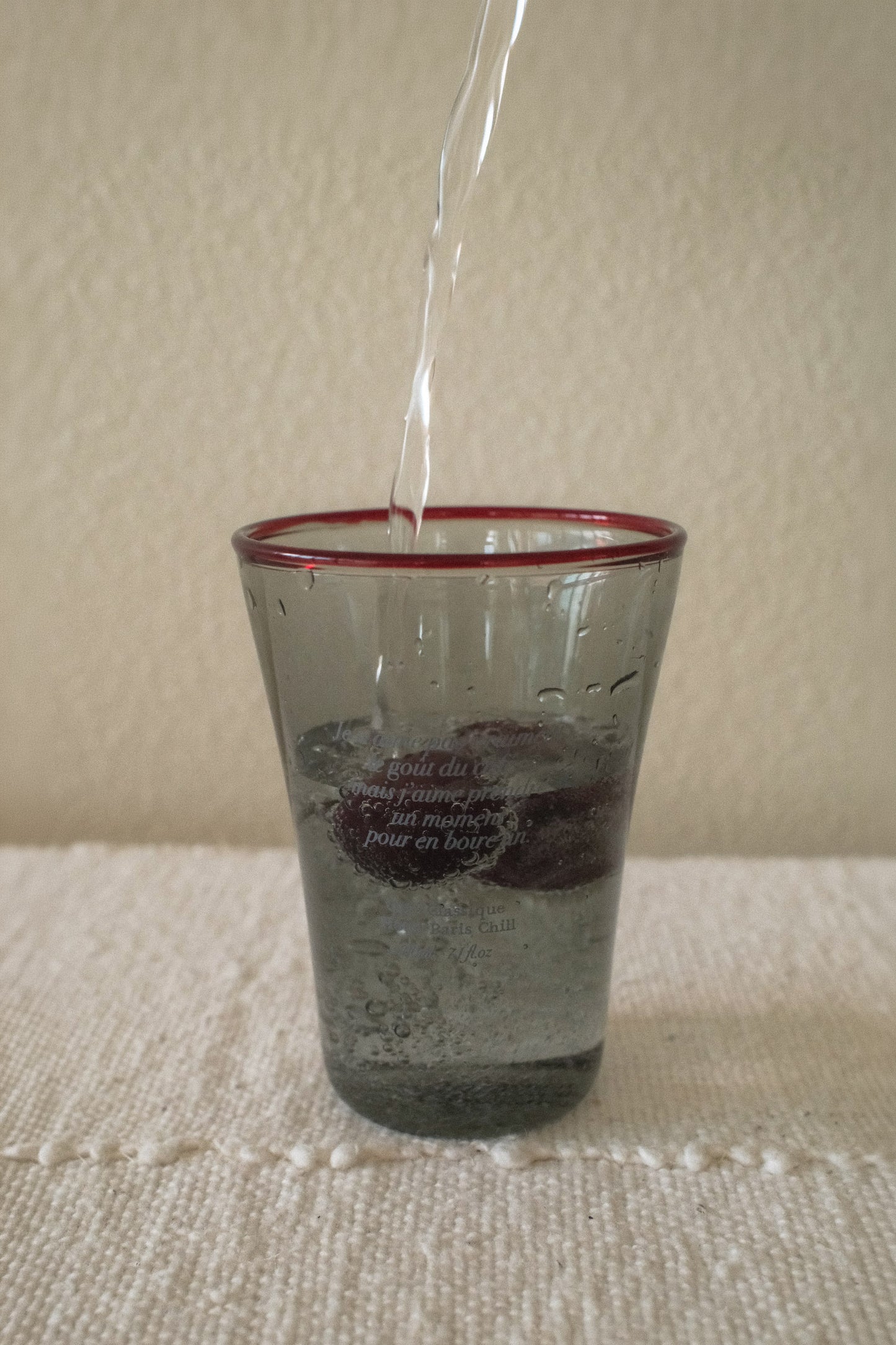 Chilled beverage served in HÔTEL827 Smokey Grey tinted glassware on a modern café table