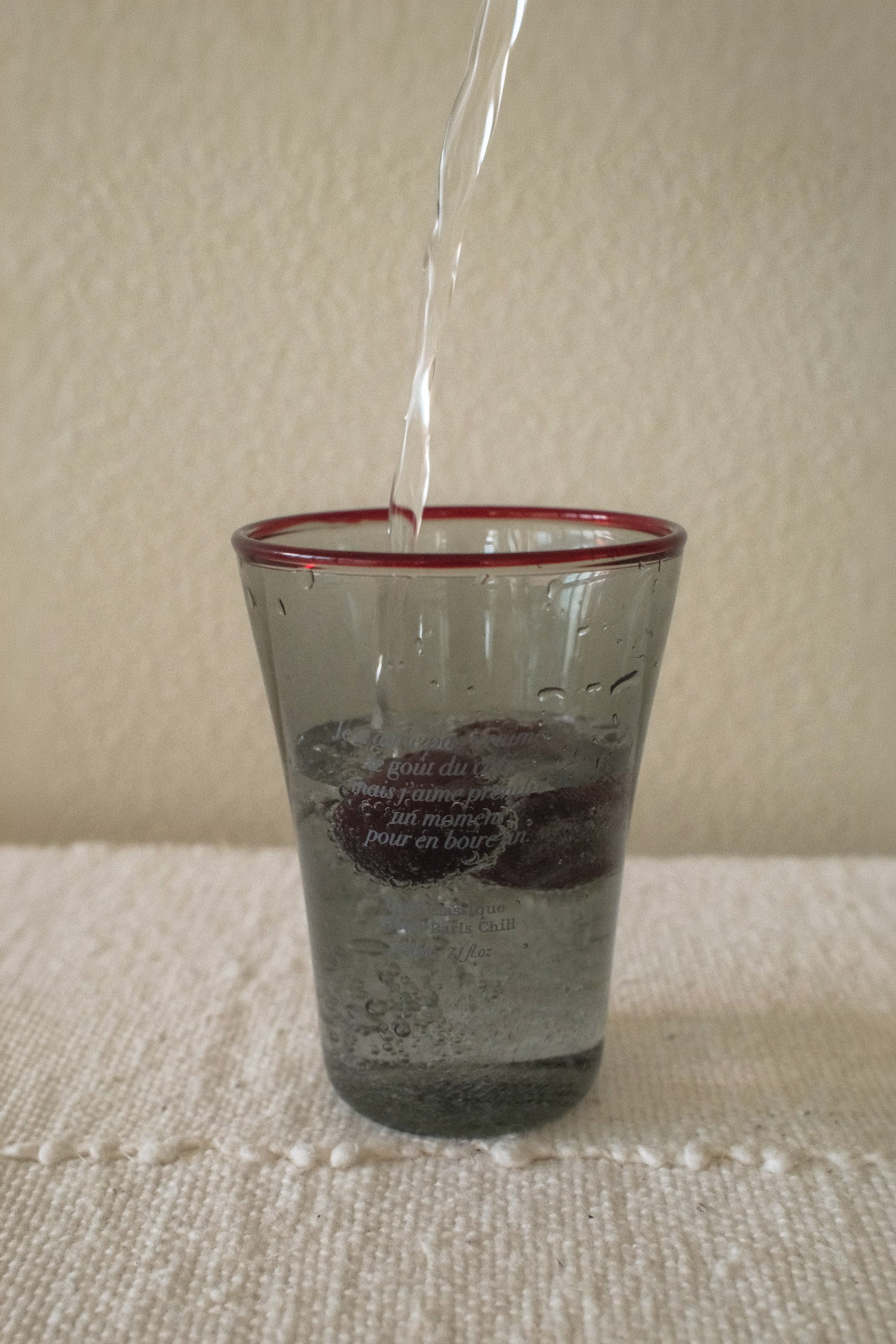 Chilled beverage served in HÔTEL827 Smokey Grey tinted glassware on a modern café table