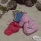 HÔTEL827 Sun Kissed baseball cap in chilli next to Hotel827 sun kissed tote bag in pink on sand. 
