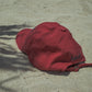 A back shot of HÔTEL827 Sun Kissed baseball cap in chilli on the sand.