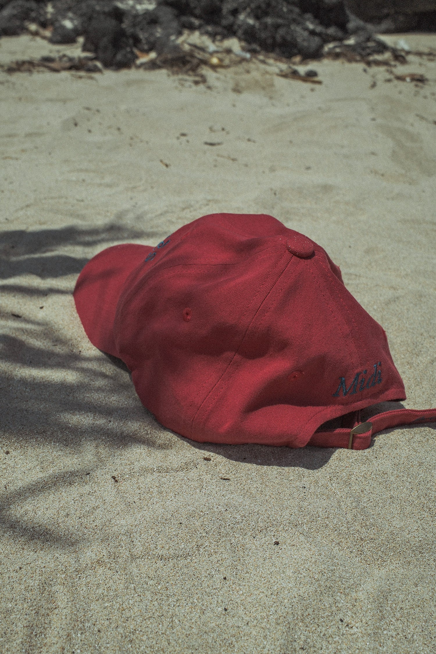 A back shot of HÔTEL827 Sun Kissed baseball cap in chilli on the sand.