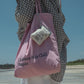 Woman wearing HÔTEL827 Sun Kissed pink canvas tote bag over shoulder pairing with a Hotel827 coin pouch.