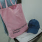 Woman wearing HÔTEL827 Sun Kissed pink canvas tote bag over shoulder, pairing with Hotel827 Sun Kissed baseball cap. 