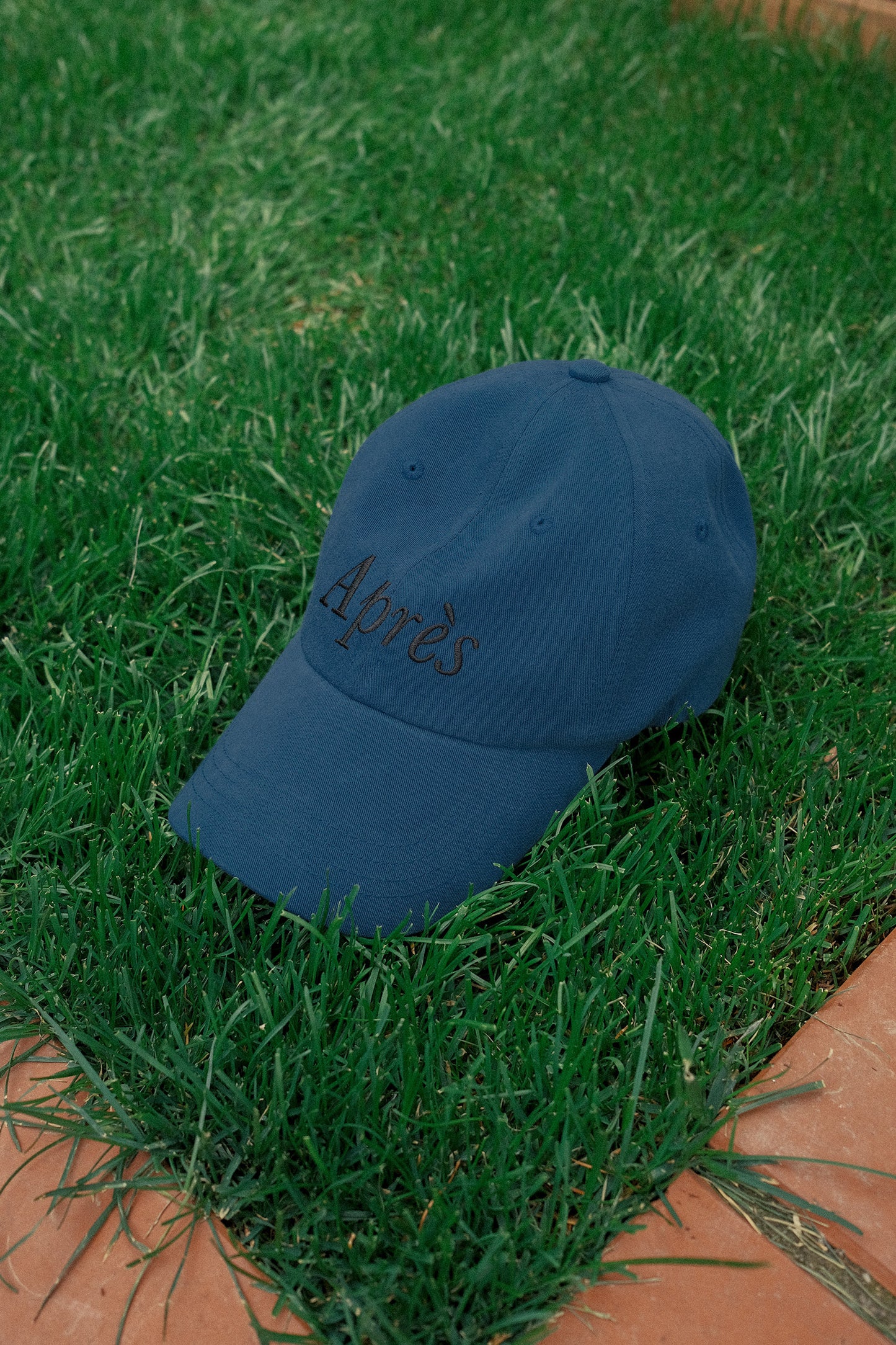 HÔTEL827 Sun Kissed blue baseball cap on the grass.