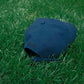 Back view of HÔTEL827 Sun Kissed blue baseball cap on the grass.