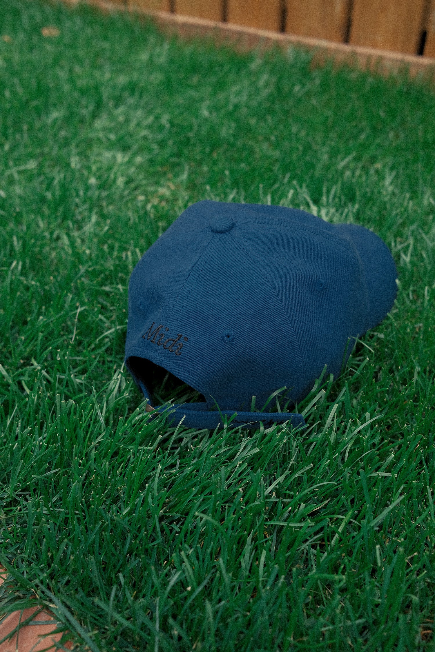 Back view of HÔTEL827 Sun Kissed blue baseball cap on the grass.