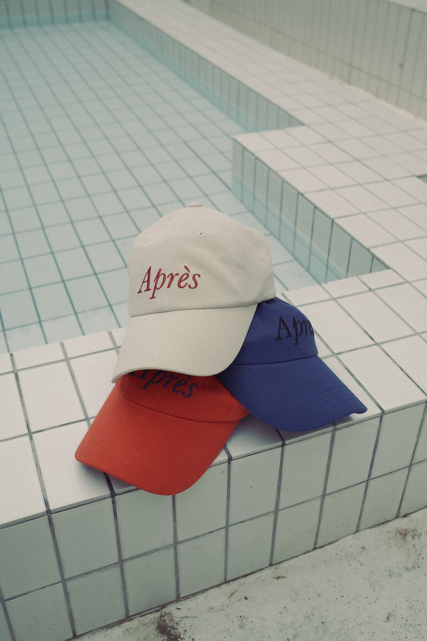 Stacked HÔTEL827 Sun Kissed baseball caps in different colours.