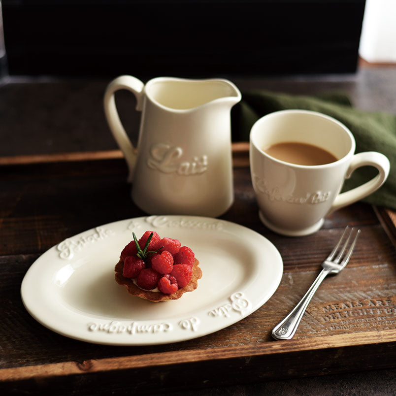 Studio M' Creamware Latte Mug in a warm cream ceramic glaze, in a table setting serving table and paired with other creamware items. 