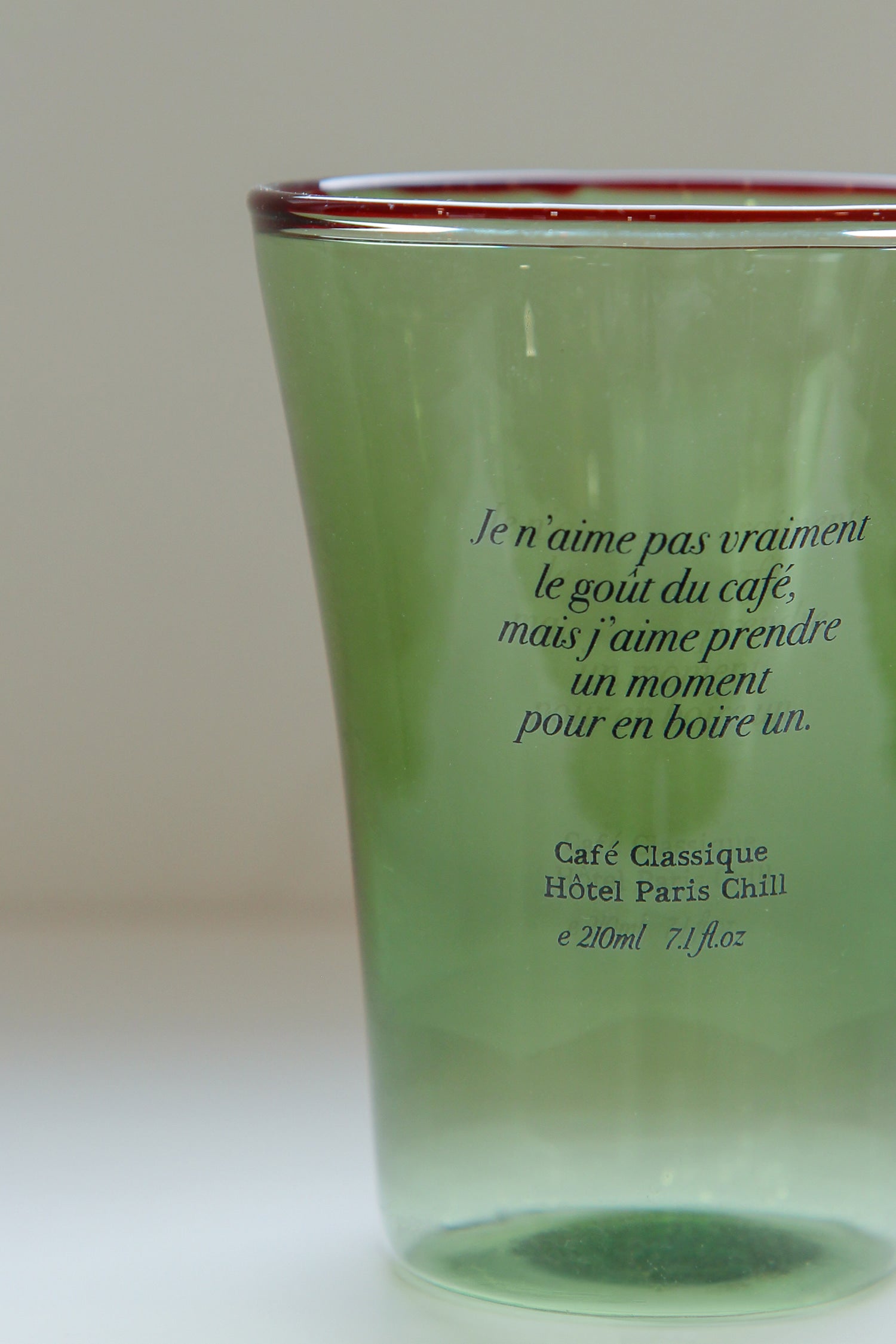 Close-up of artisanal mouth-blown ripples and typography on HÔTEL827 olive glass cup