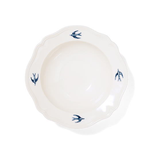 Studio M' Early Bird 170 porcelain bowl featuring a hand-painted blue swallow relief on a scalloped floral rim, a shot from the aerial angle. 