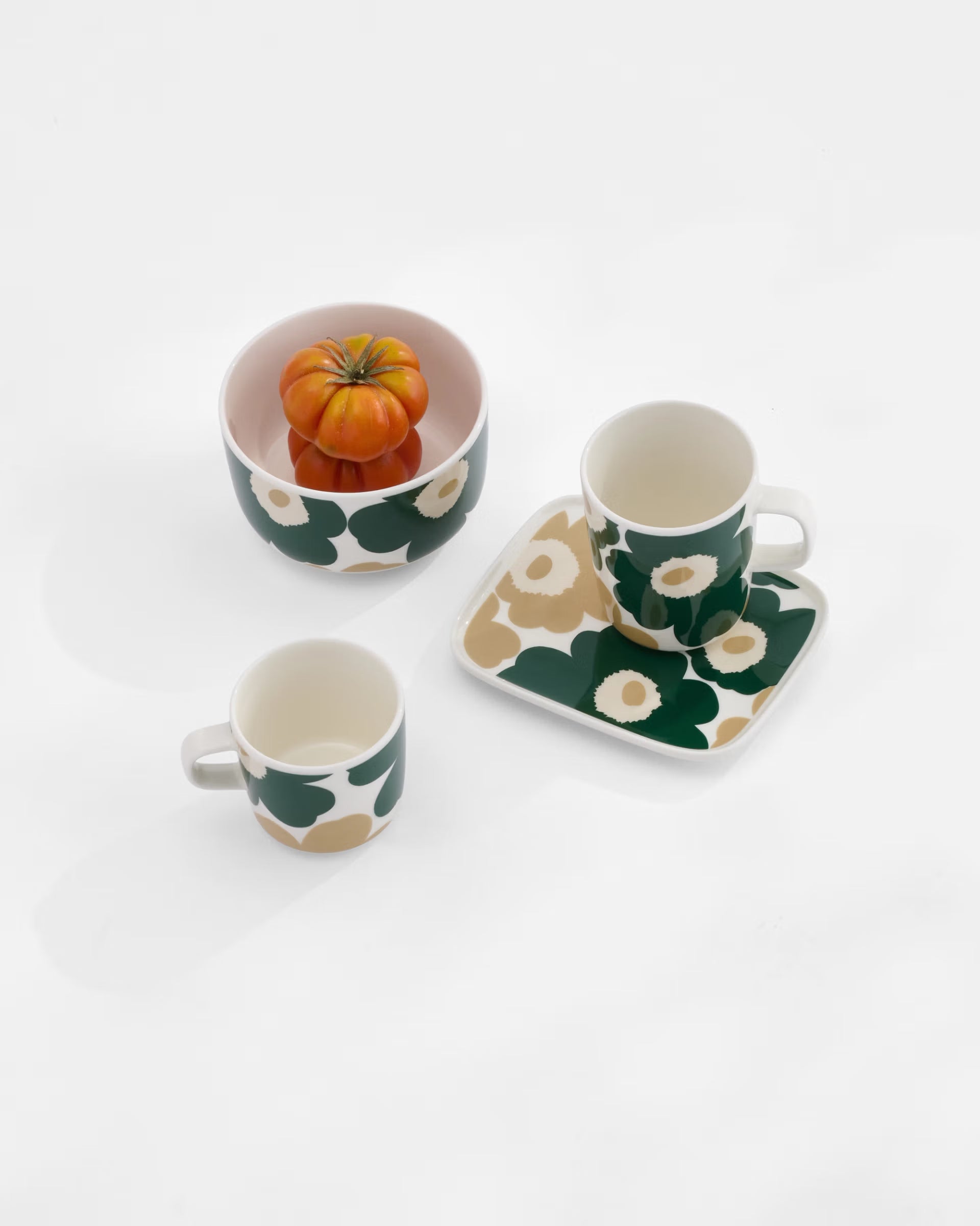 A lifestyle shot of the Marimekko Oiva collection featuring the iconic Unikko poppy print in dark green, beige, and light sand.