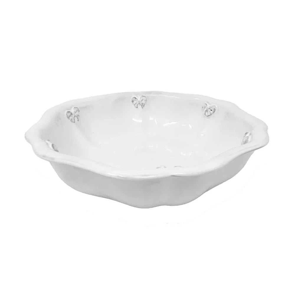 A 21cm handmade milky-white ceramic salad bowl by Carron Paris, featuring a sculpted Marie-Antoinette ribbon and knot design around the outer rim. A photo taken from the side angle.