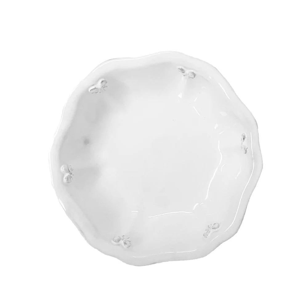 A 21cm handmade milky-white ceramic salad bowl by Carron Paris, featuring a sculpted Marie-Antoinette ribbon and knot design around the outer rim. A photo taken from the high angle.