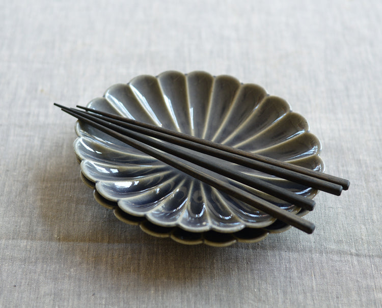 A lifestyle photo of back of Studio M' Lacquered Chopsticks 23cm featuring a sleek, minimalist profile and a subtle matte black wipe-lacquer finish over natural wood grain.